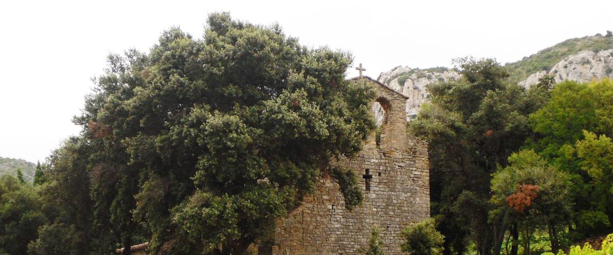 A stone tower surrounded by lush greenery and a cross on top.