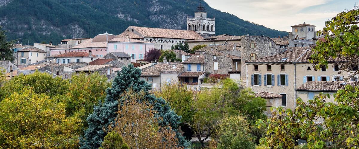 A mountainous village with historic buildings and a prominent tower.