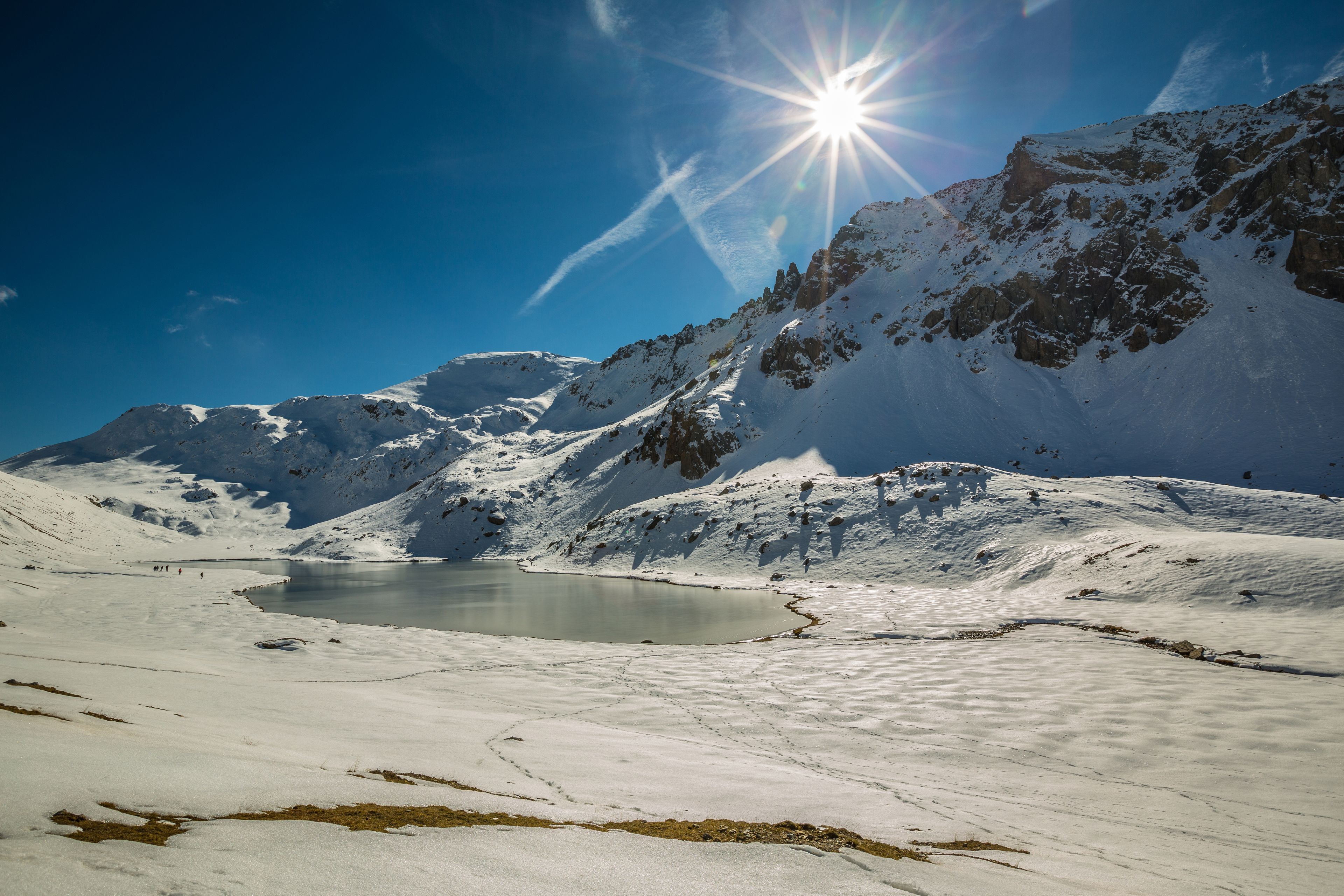Un paysage de montagne enneigé, avec un ciel dégagé et un petit lac.