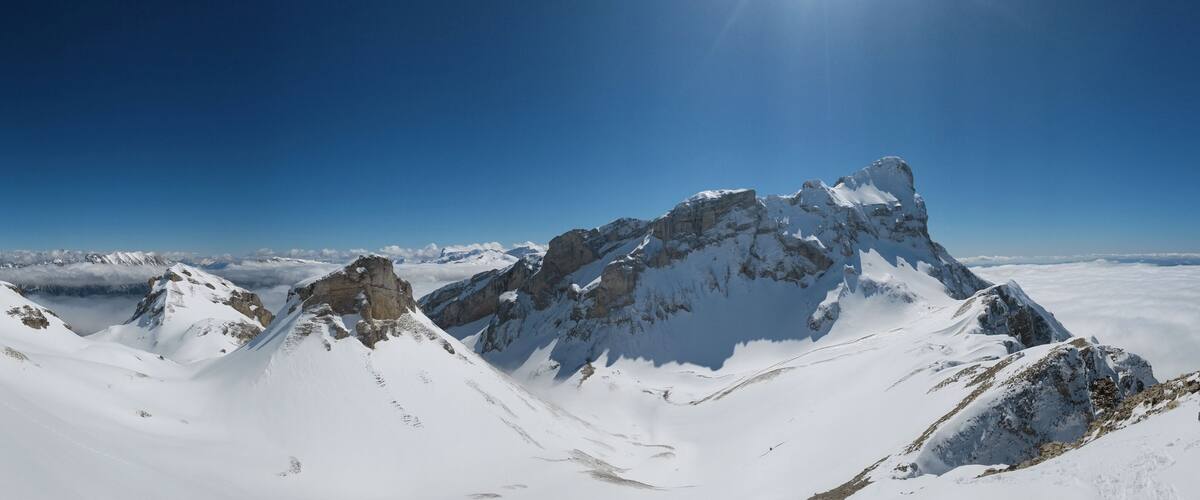 A snow-covered mountain range with sharp peaks and a clear blue sky.