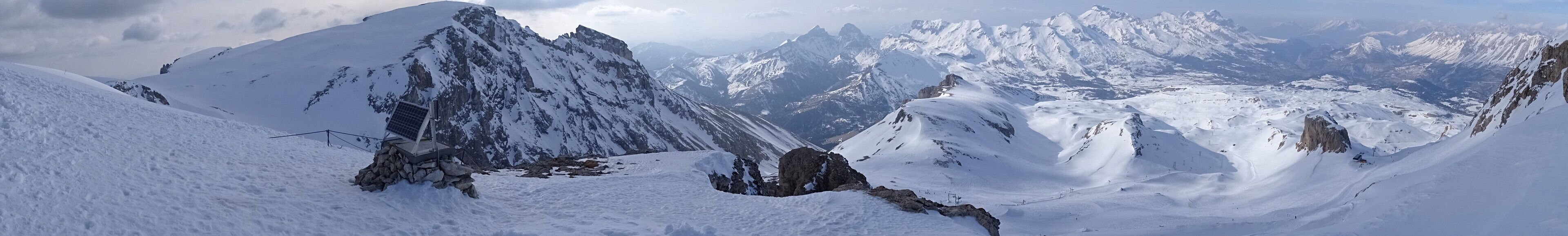 A snow-covered mountain range with sharp peaks and rocky outcrops.