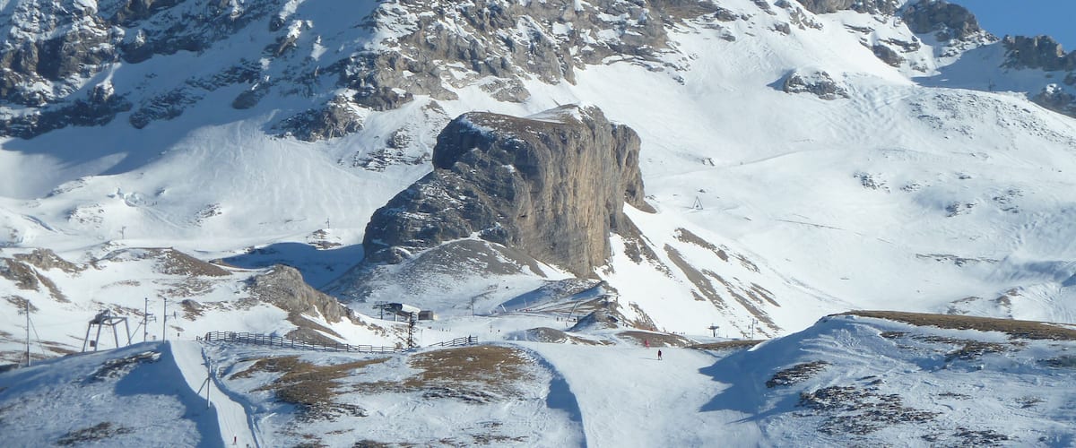 A snow-covered mountain with a rocky outcrop and ski slopes.