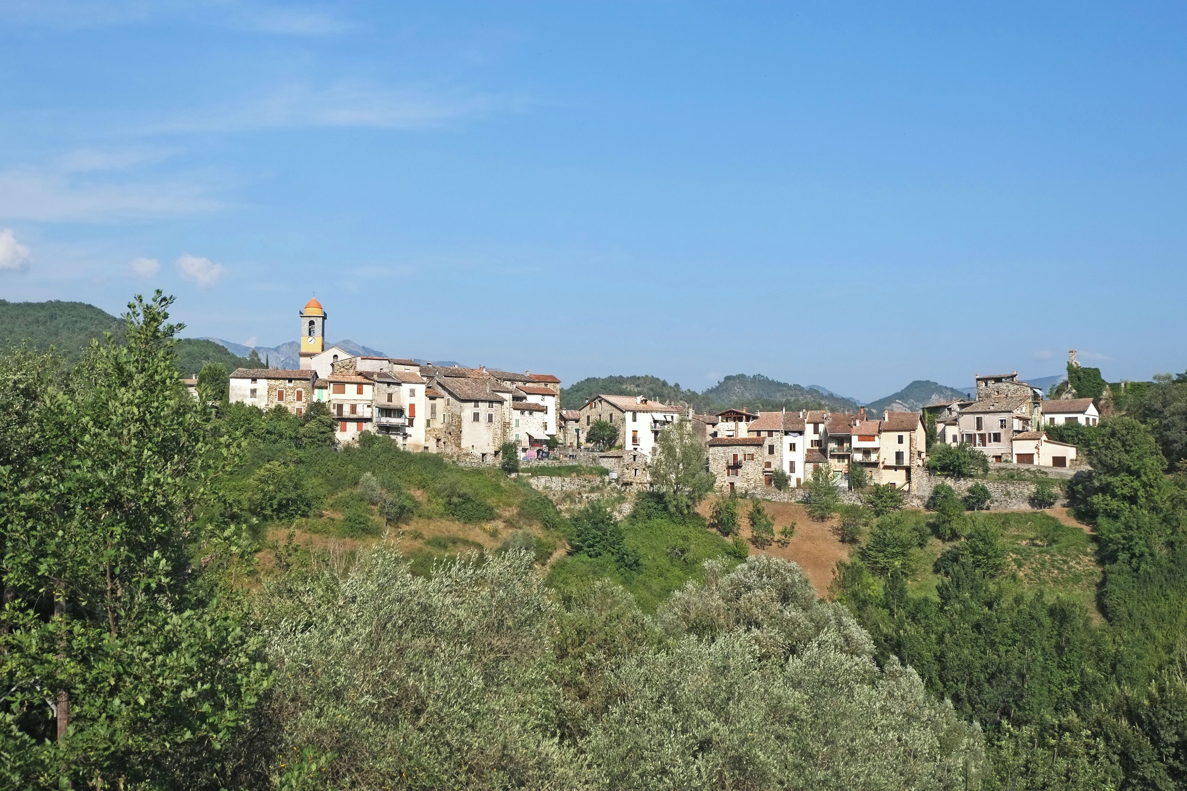A hillside village with traditional buildings and a church tower.