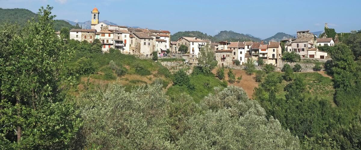 A hillside village with traditional buildings and a church tower.