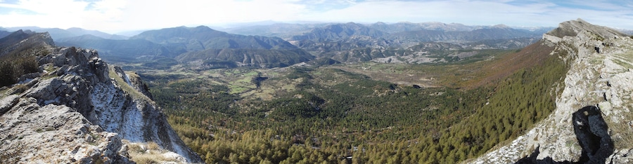 Un paysage montagneux caractérisé par des pics rocheux et des forêts denses.
