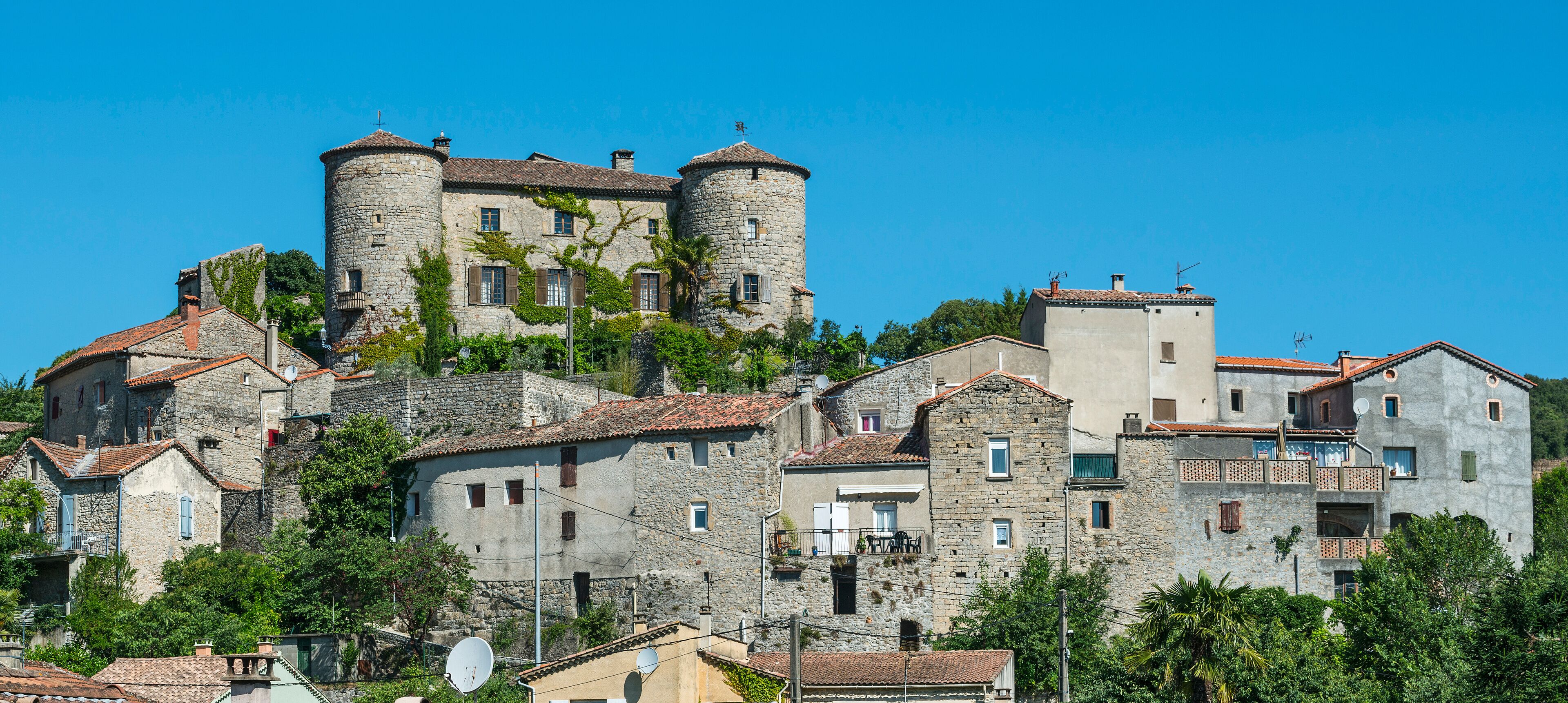 A historic town with stone buildings, a prominent tower, and lush greenery.