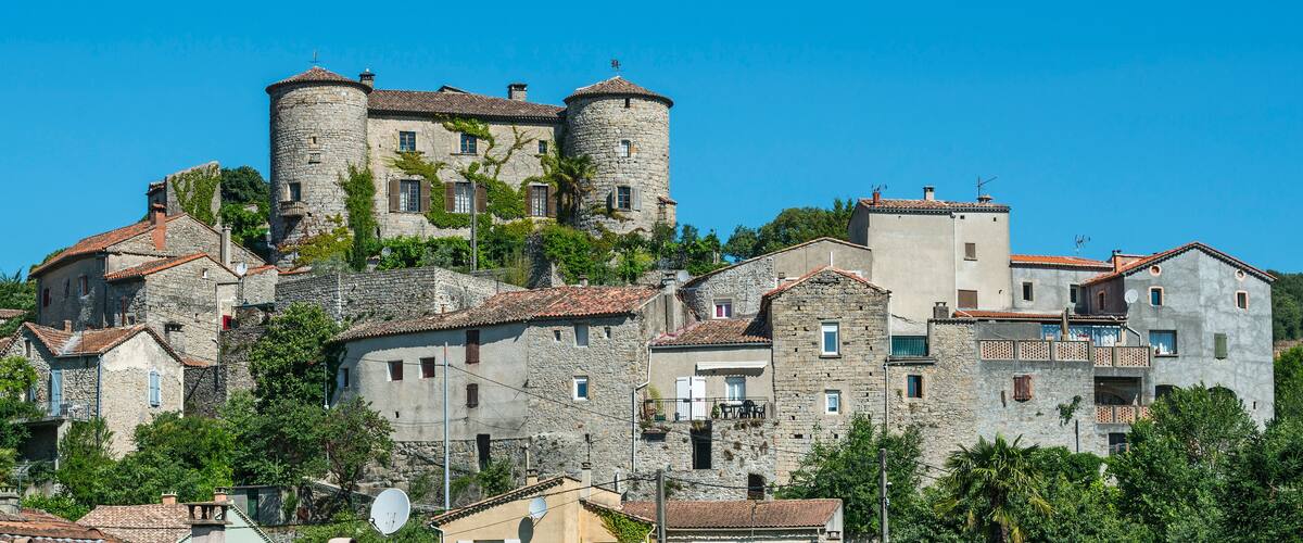 A historic town with stone buildings, a prominent tower, and lush greenery.