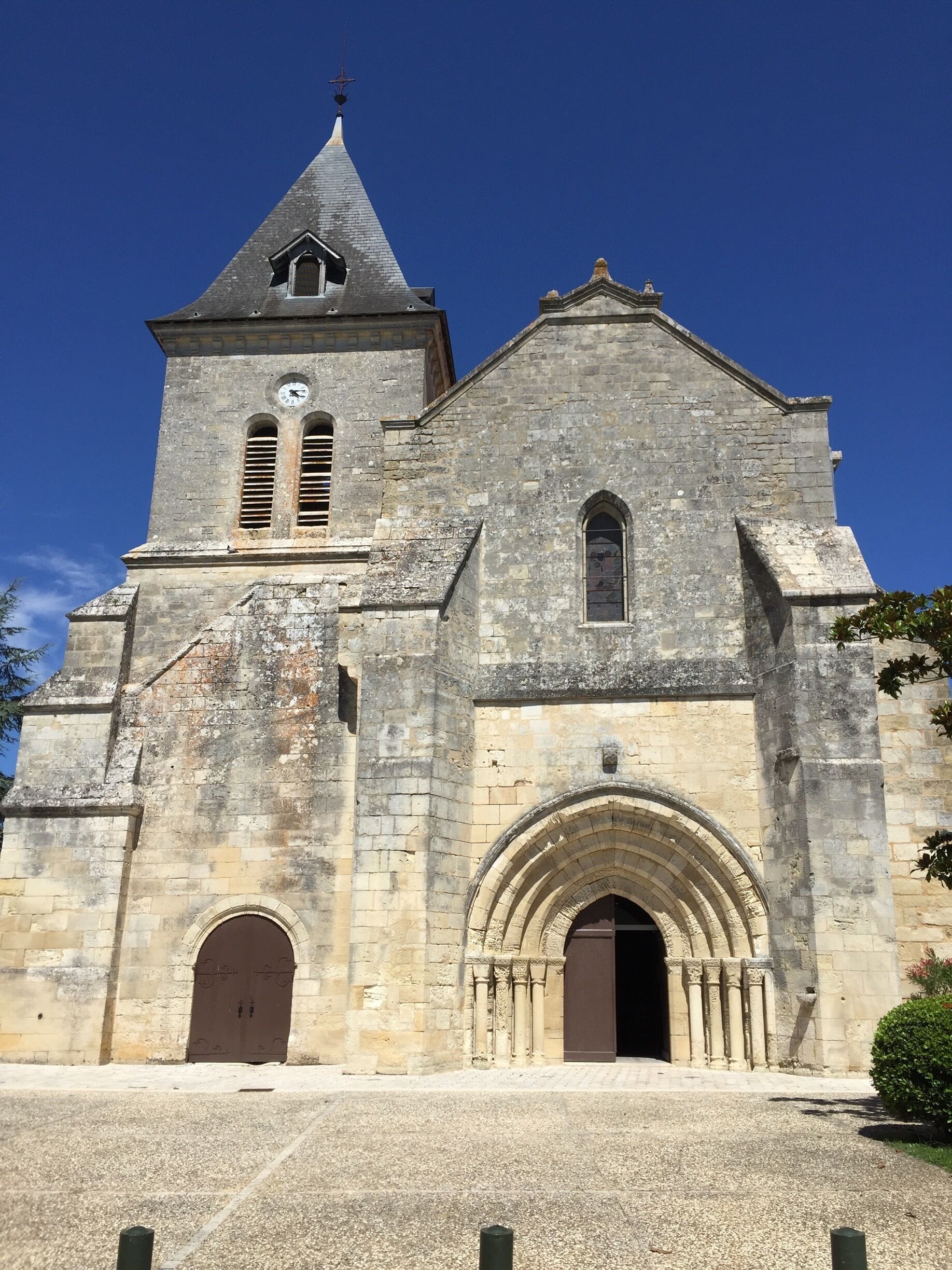 A historic stone church with a bell tower, arched entrance, and a clock.