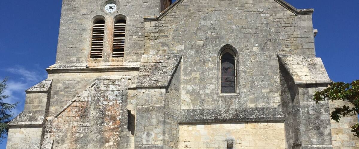 A historic stone church with a bell tower, arched entrance, and a clock.
