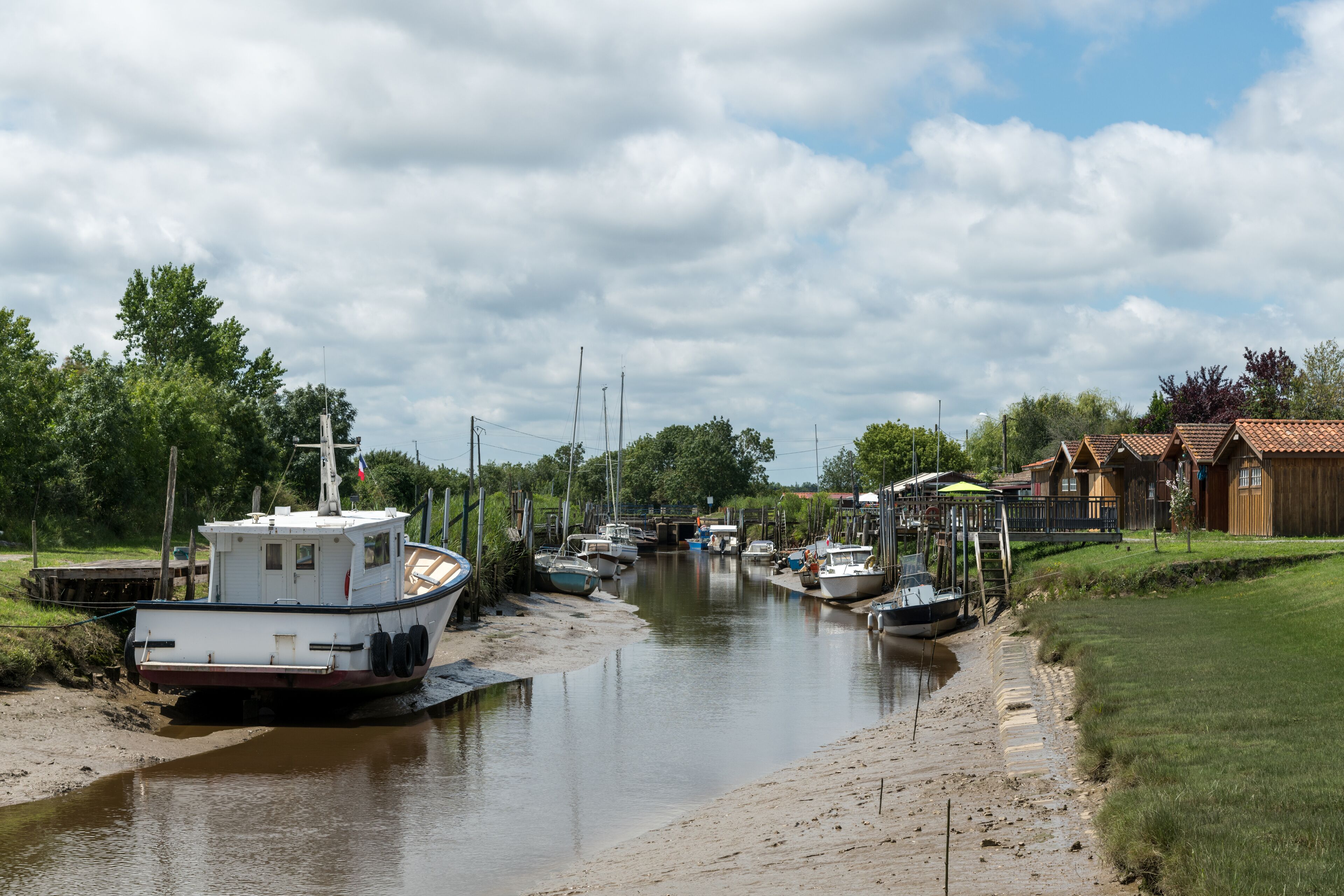 A canal with boats docked on the left and houses on the right.