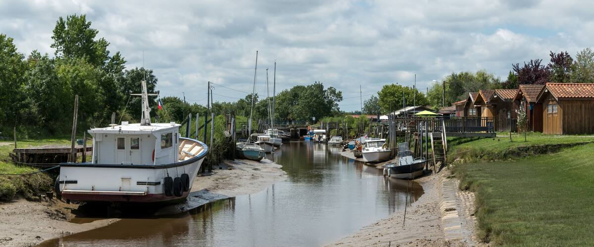 A canal with boats docked on the left and houses on the right.