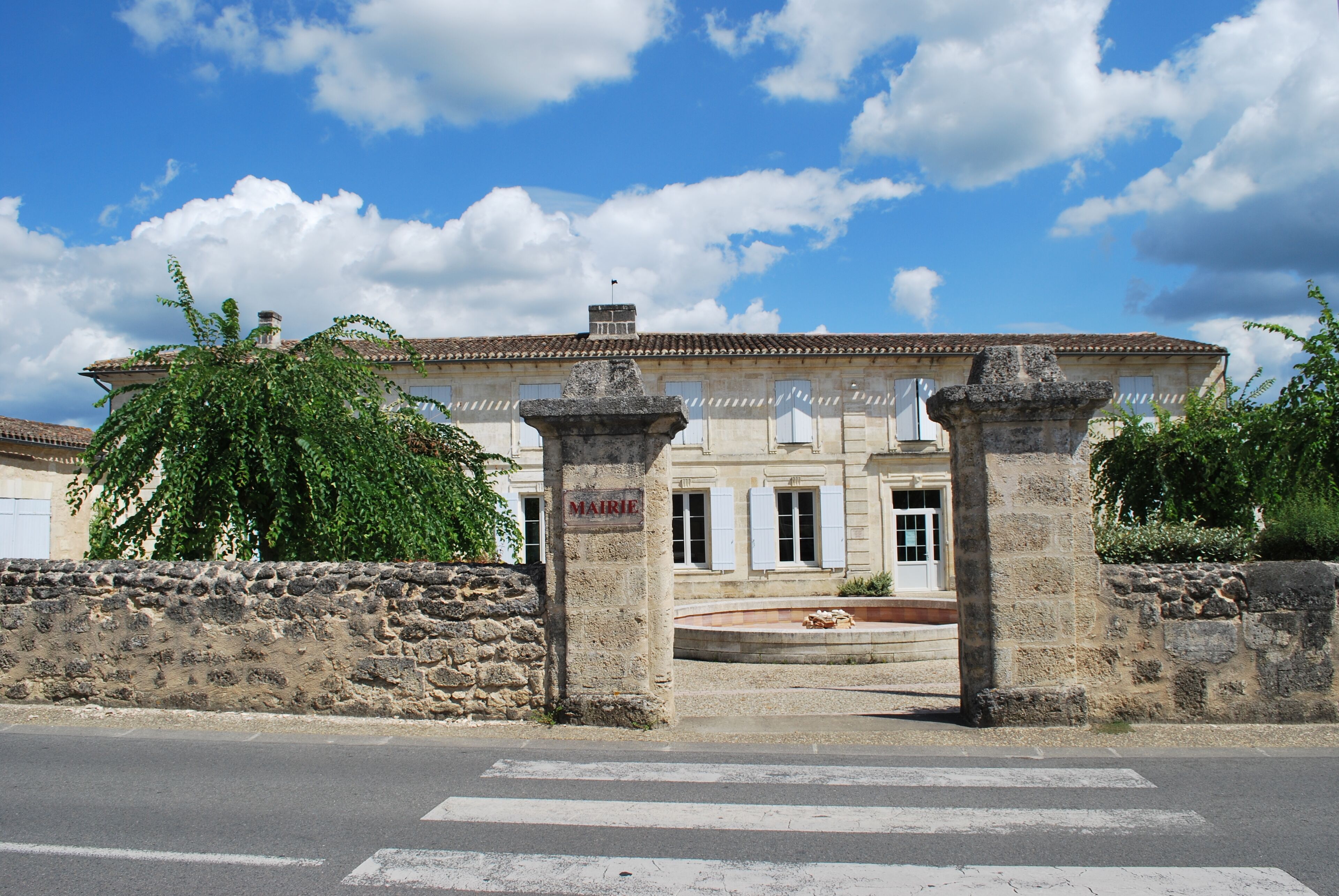 A historic building with a stone facade, a stone gate, and a clear blue sky with clouds.