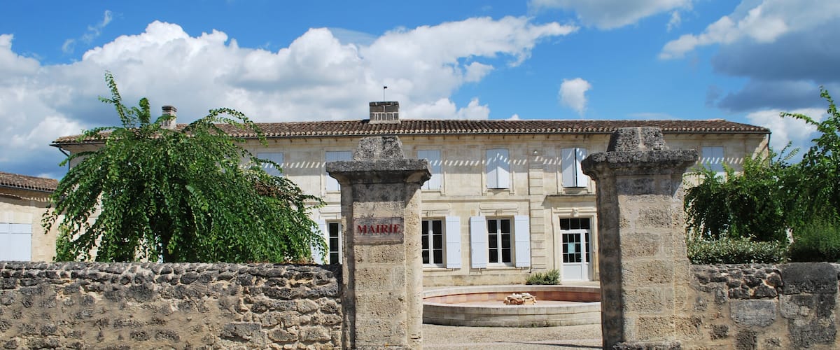 A historic building with a stone facade, a stone gate, and a clear blue sky with clouds.