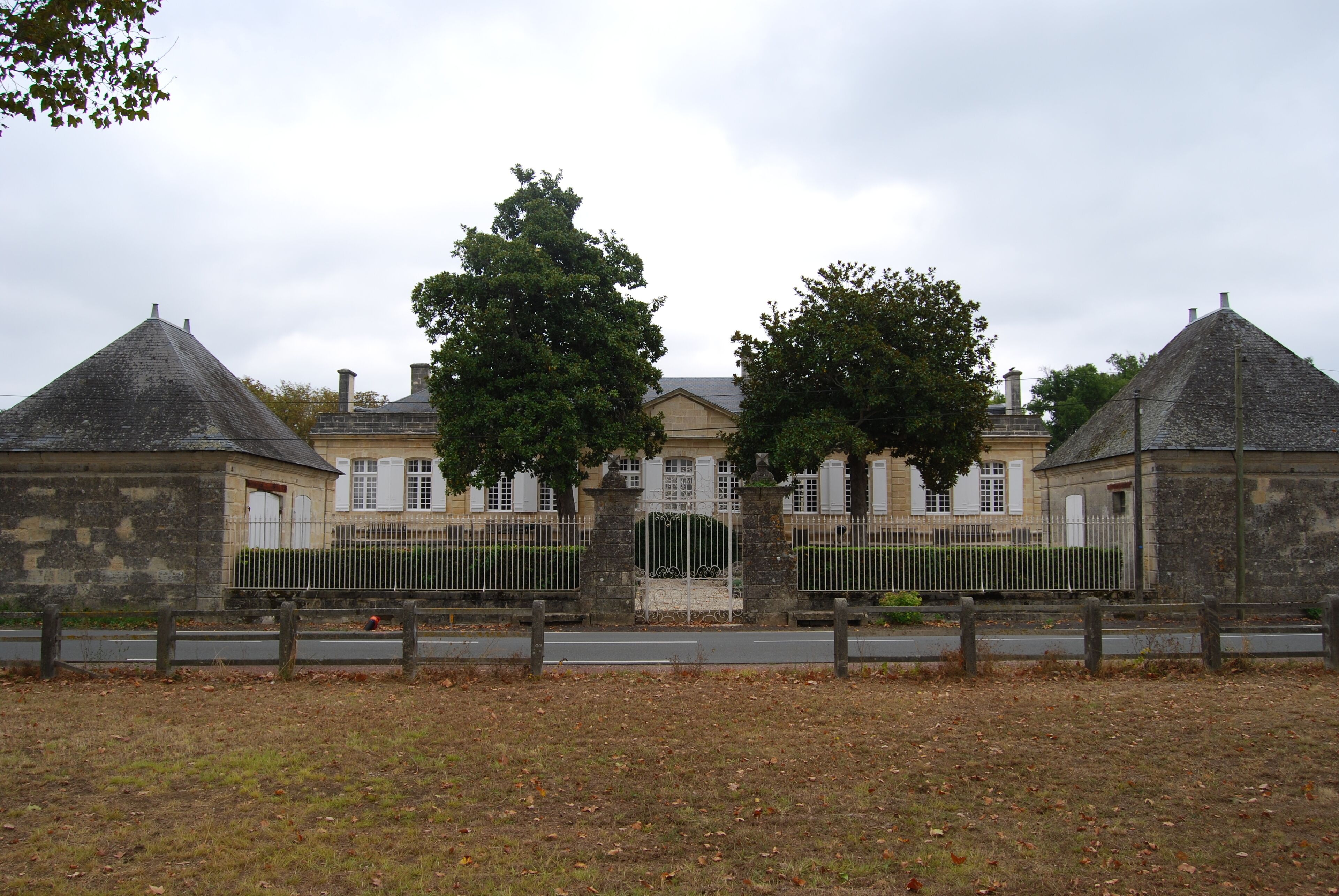 A large stone building with a central entrance, flanked by two smaller structures with conical roofs.