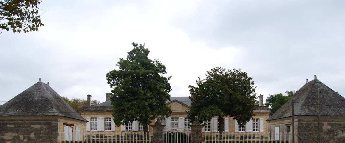 A large stone building with a central entrance, flanked by two smaller structures with conical roofs.