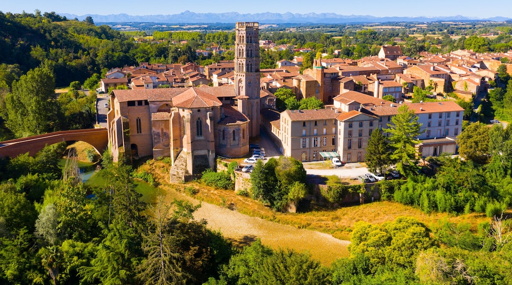 Scenic aerial view of Rieux-Volvestre town on banks of small tributary of Garonne in summer overlooking ancient Roman Catholic Cathedral, France