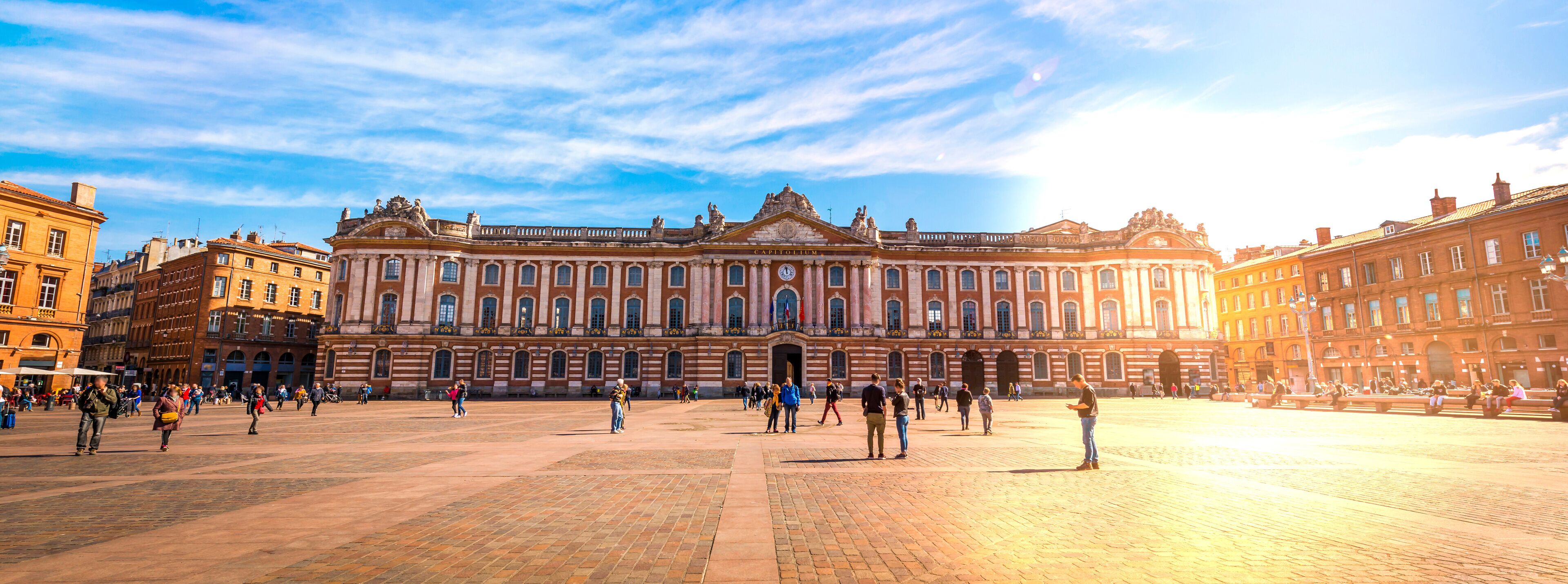 The Royal Palace of Madrid with a large open plaza and people walking around.