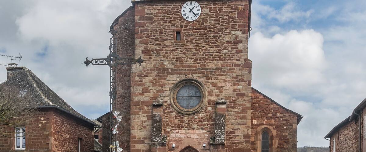 A historic church with a clock tower, a large arched doorway, and a stone facade.