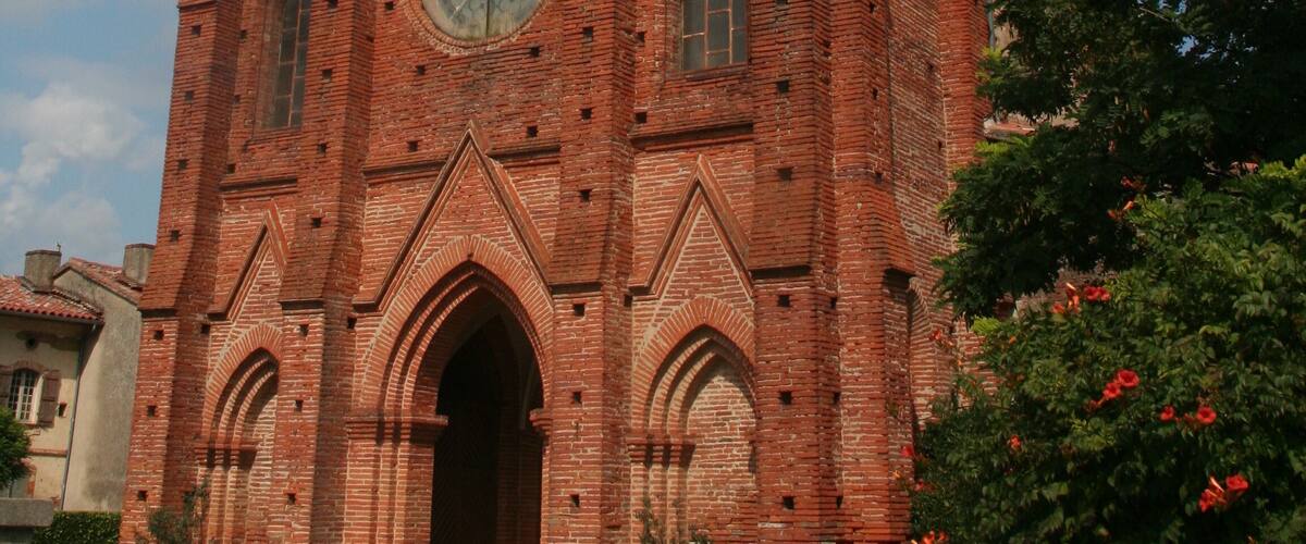A red brick church with a tall tower and a large circular window.