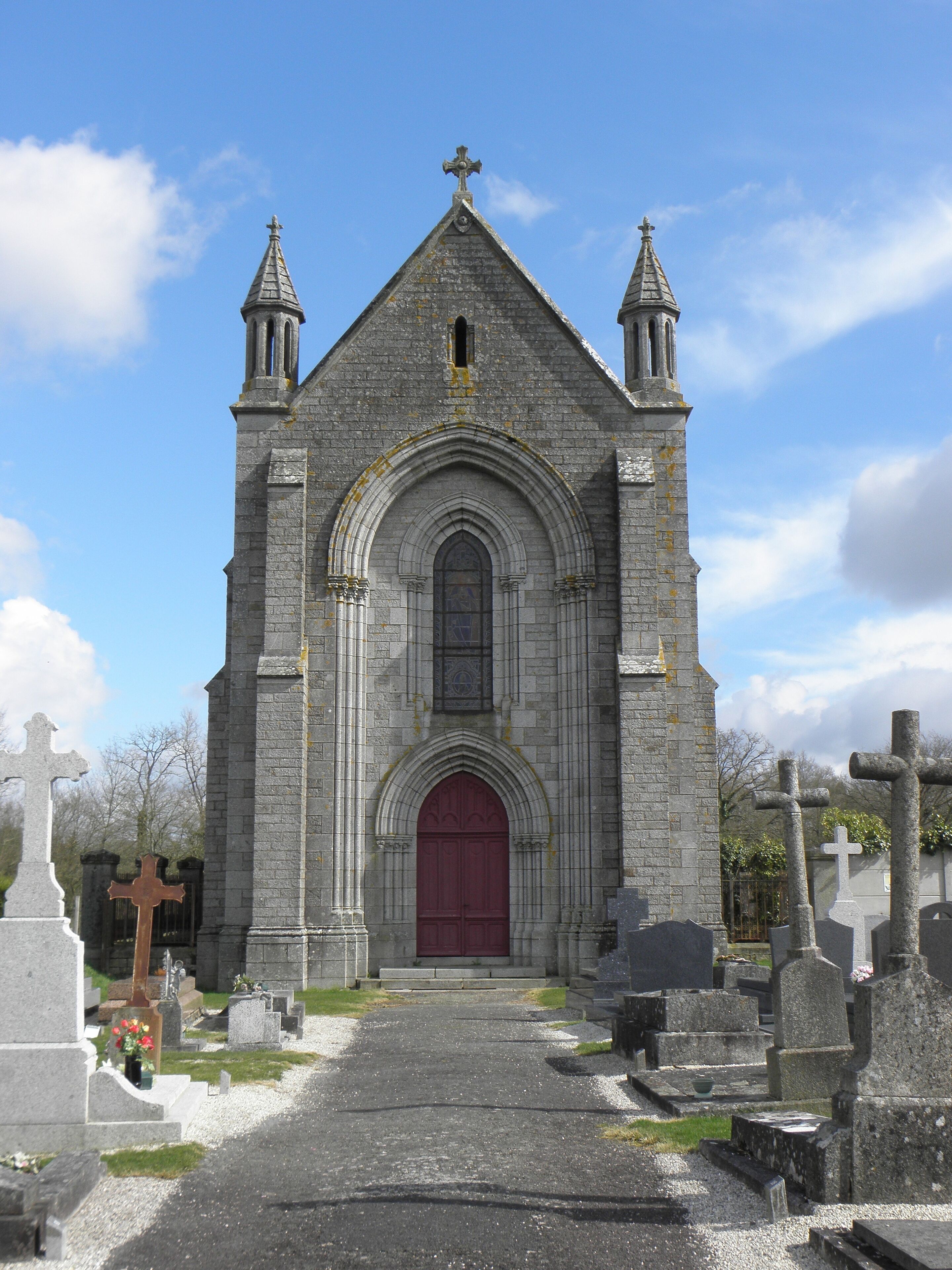 A stone church with a red door and two towers.