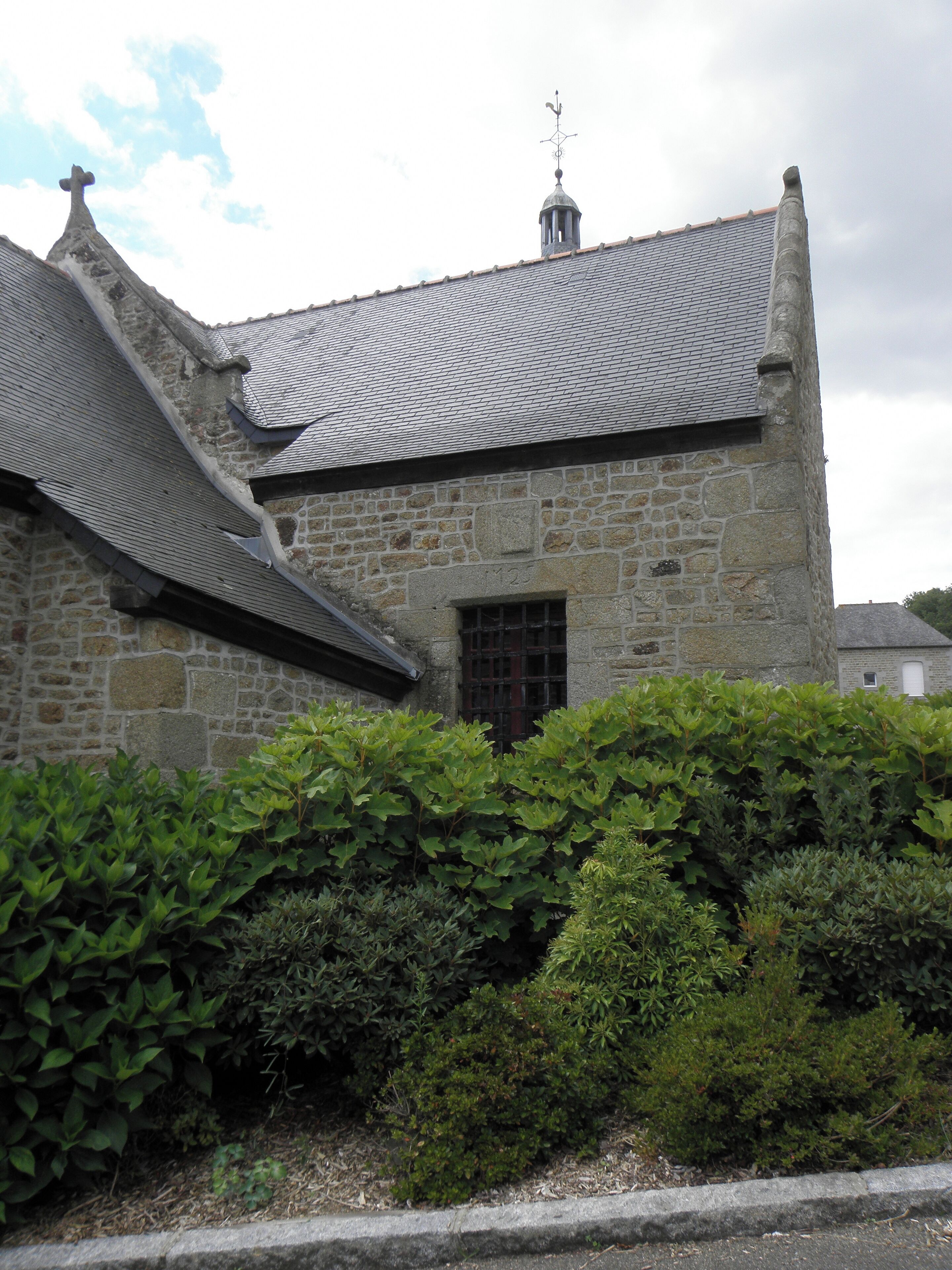 A stone building with a tiled roof and a weather vane.