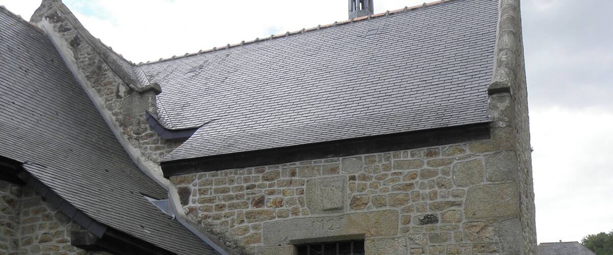 A stone building with a tiled roof and a weather vane.