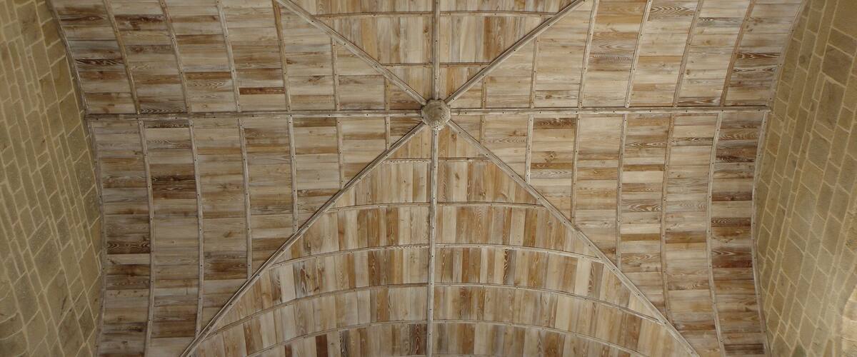 A wooden ceiling with a geometric pattern and a brick wall.