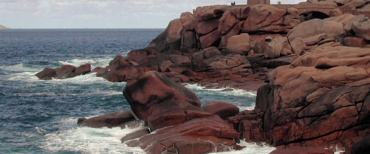 A rocky coastline with a lighthouse on a cliff.