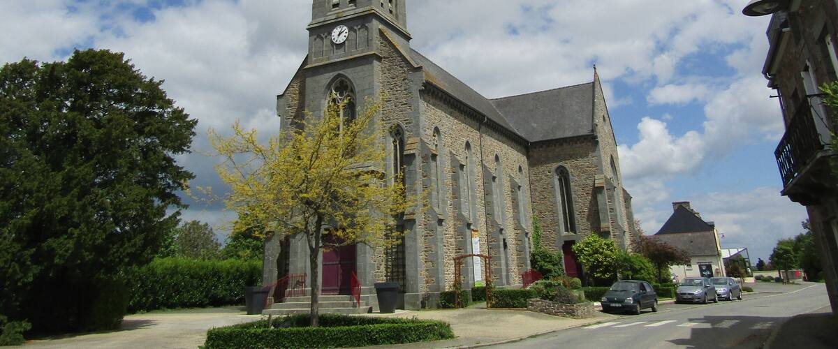 A historic church with a tall spire and clock tower, surrounded by trees and parked cars.