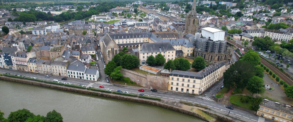A river running through a historic town with old buildings and a church spire.