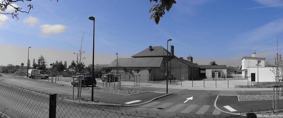 A roundabout with modern buildings, a clear sky, and a fence along the road.
