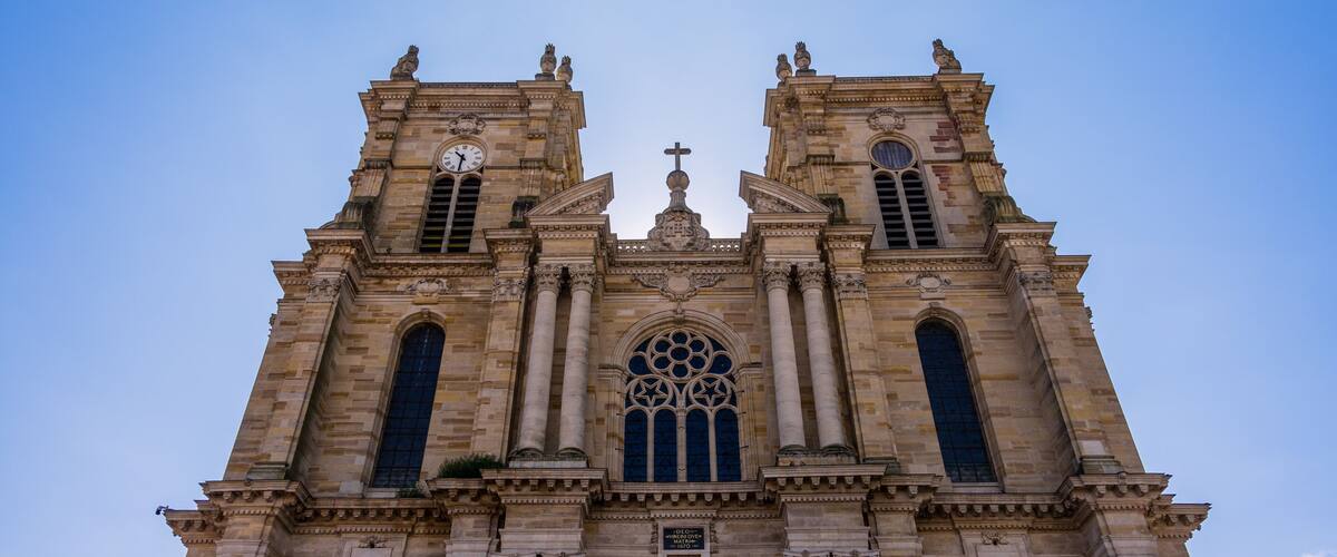A historic cathedral with twin towers, a central rose window, and a cross on top.