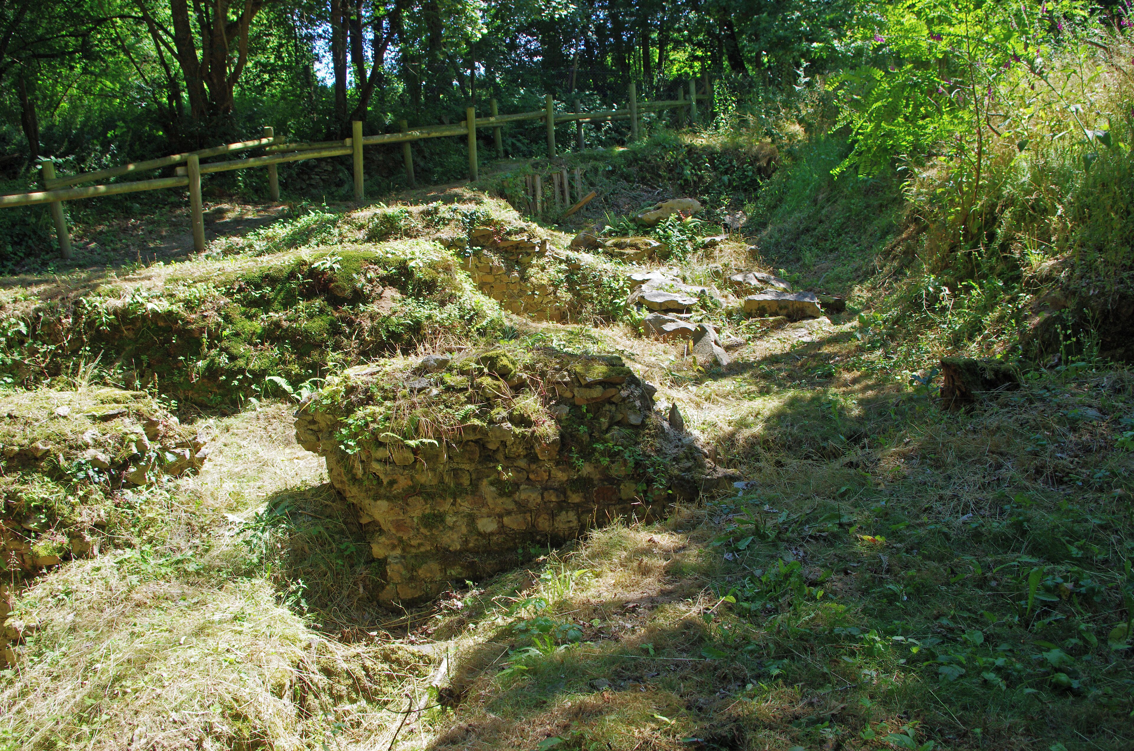 Amphithéâtre Gallo-Romain de Gennes (Maine-et-Loire). C'est un demi amphithéâtre adossé à la colline de Mazerolles au sud du bourg de Gennes. Des fouilles récentes montrent que cet amphithéâtre construit à la fin du pemier siècle fut utilisé jusqu'au début du troisième siècle (comme l'indique les éléments mobiliers, monnaies et poteries, retrouvés). La cavea* est uniquement constituée de la pente du coteau. Restes des importantes fondations (1,5 m de large) du mur de façade qui entourait la cavea. Cavea : Dans un amphithéâtre romain c'est la partie formée par les rangées de gradins où s'asseyaient les spectateurs. Amphitheatre Gallo-Romain of Gennes (Maine-et-Loire). This is a semi amphitheater backs onto the hill of Mazerolles south of the town of Gennes. Recent excavations indicate that this amphitheater built in the late 1st century was used until the early third century (as indicated movable Elements, coins and pottery, find yourself). The cavea* is only constituted the slope of the hillside. Ruins of major foundations (1.5 m wide) of the front wall standing all round the cavea. Cavea: In a Roman amphitheater is the area formed by the rows of bleachers where spectators sat.