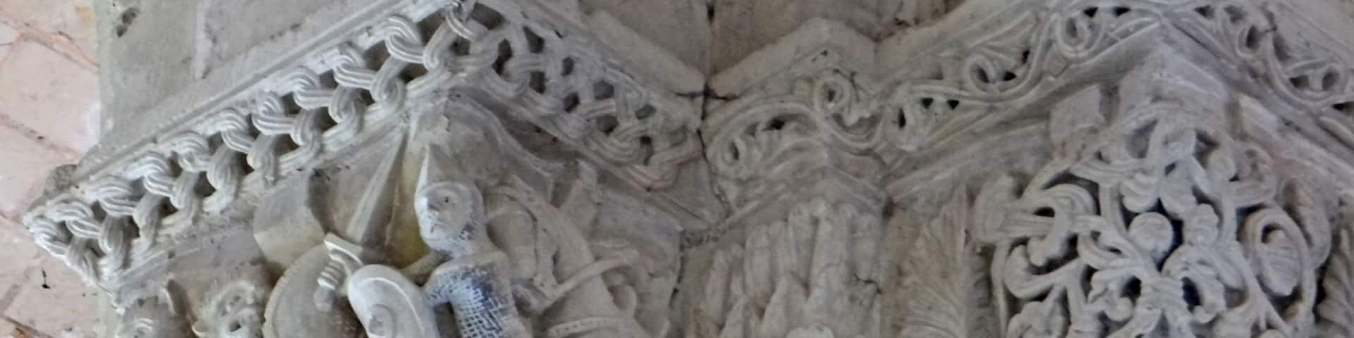 Chapiteaux dans la nef de l'église Le personnage avec un bouclier, une épée, une côte de maille et un cheval pourrait être un croisé (Foulque V (?), comte d'Anjou et du Maine) qui combat un barbare ou un être monstrueux.