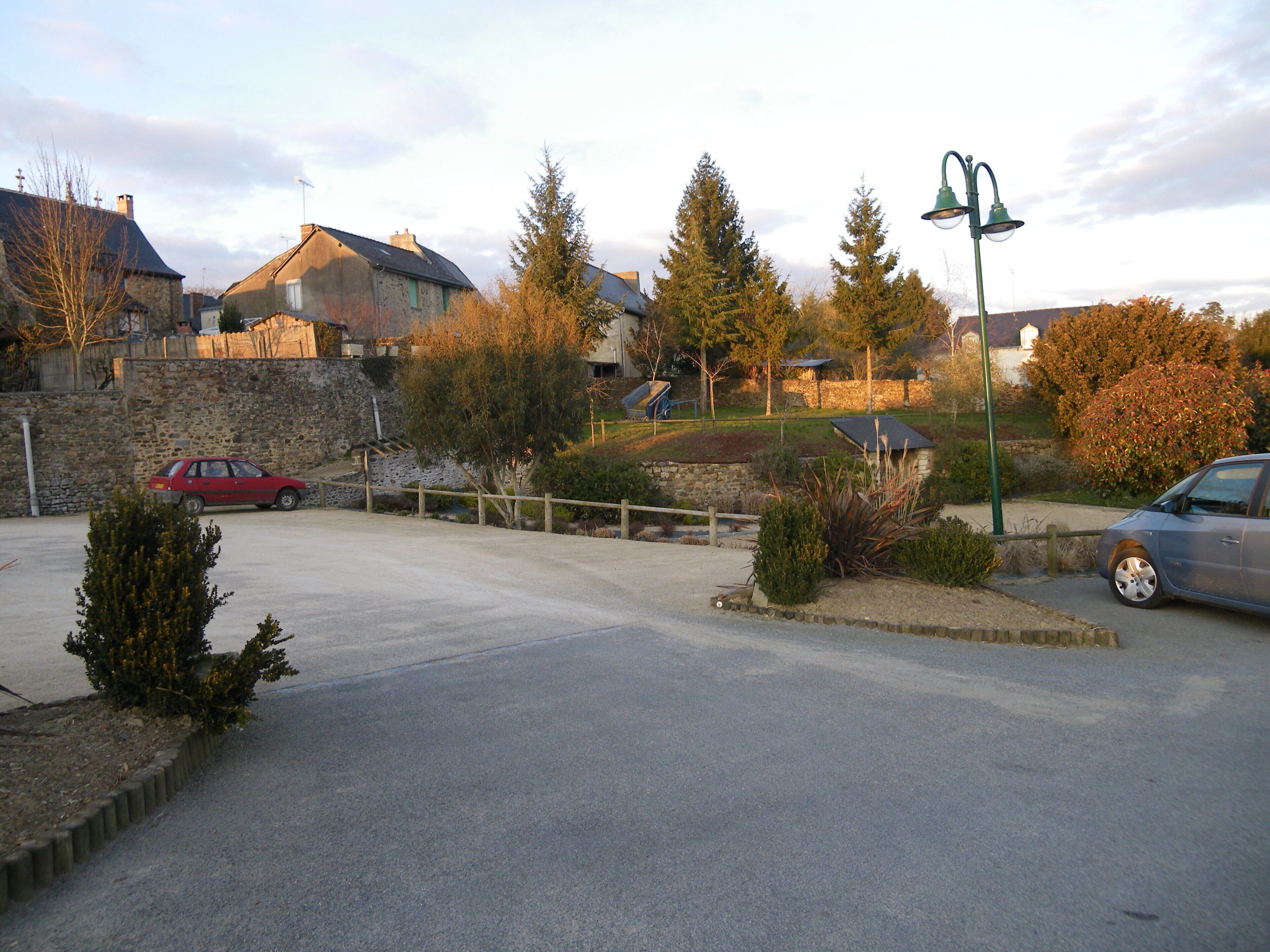 A residential area with houses, a red car, and a blue car parked on the street.