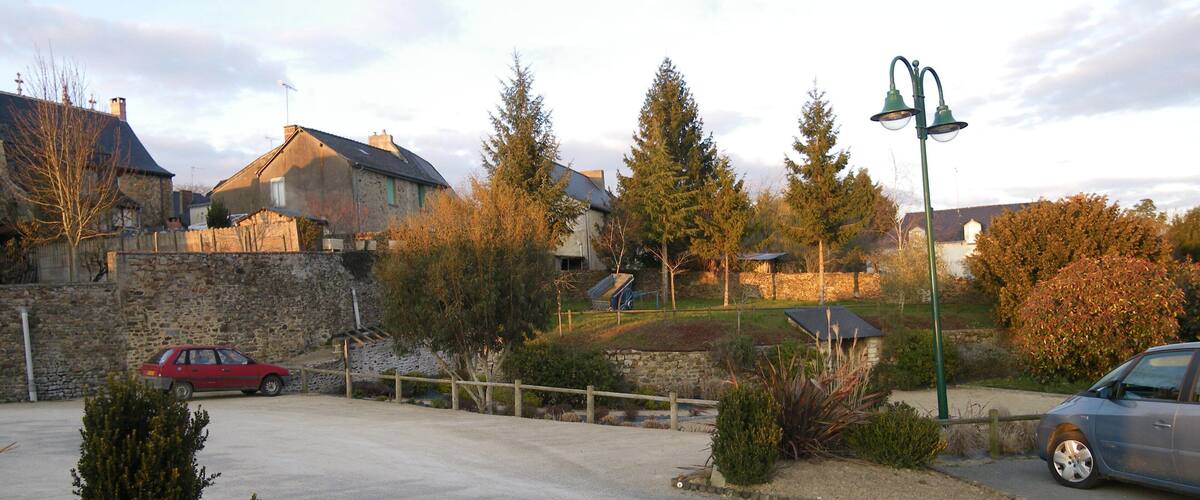 A residential area with houses, a red car, and a blue car parked on the street.