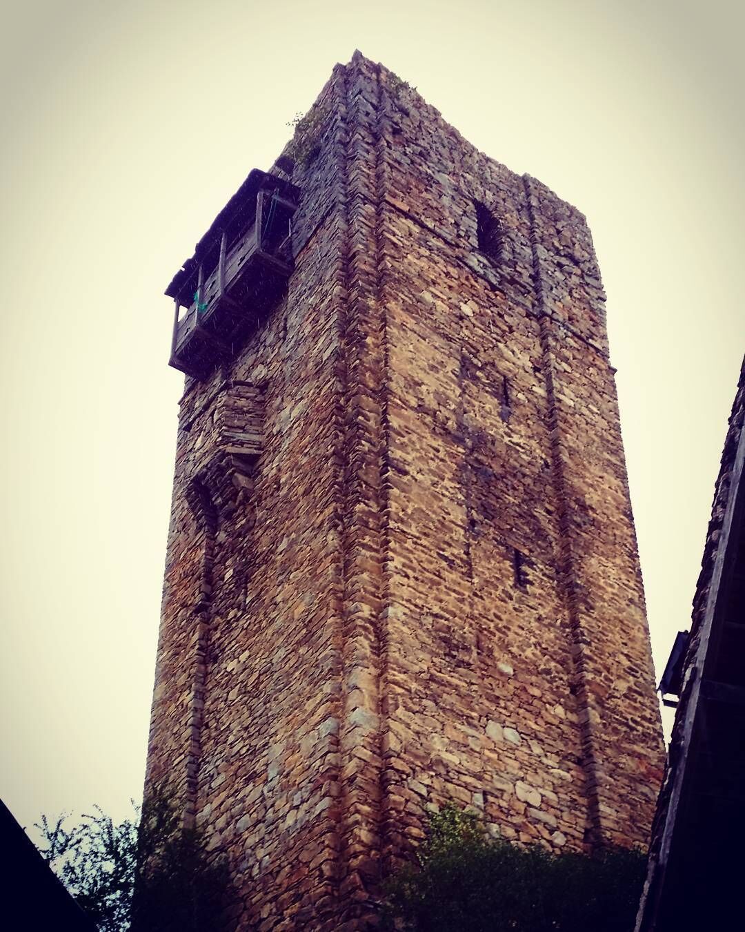 A tall stone tower with a wooden platform on the upper level.