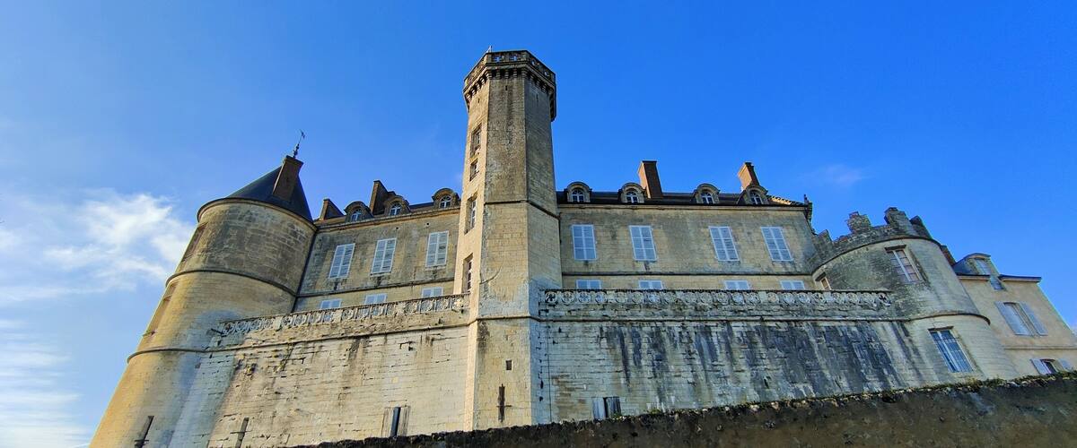 A historic castle with a prominent tower, crenellated walls, and a clear blue sky.