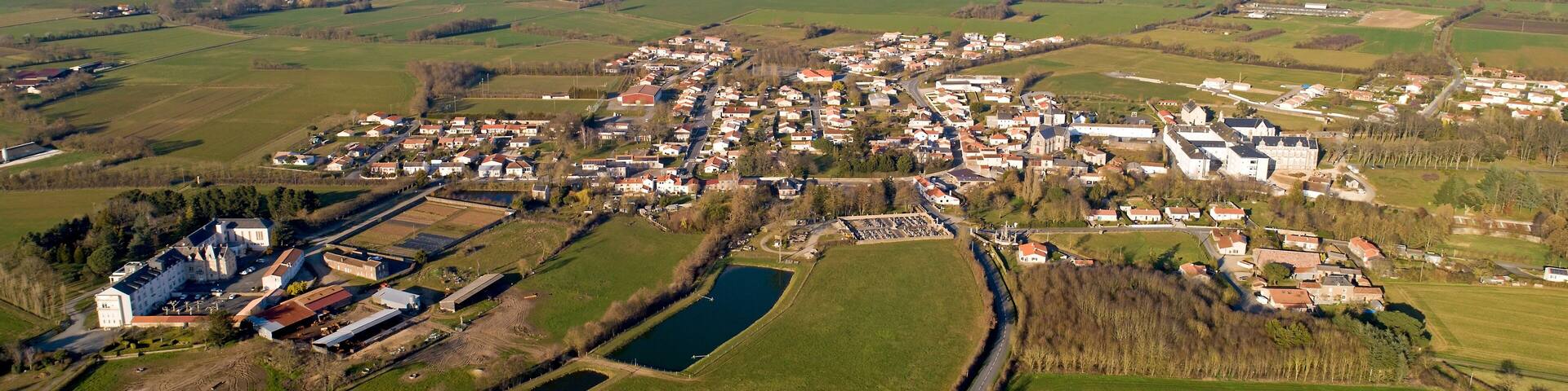 An aerial view of a rural town with a church, fields, and a small lake.
