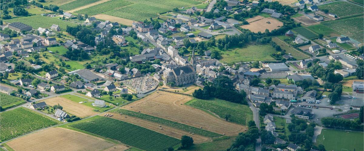 An aerial view of a rural village with vineyards, houses, and a prominent church.