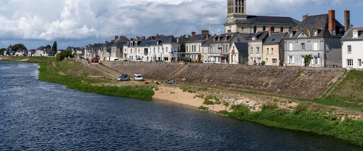 A riverside town with historic buildings and a prominent church tower.