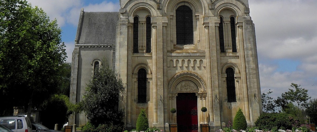 A historic church with a tall steeple, a clock, and a red door.
