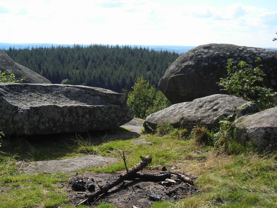 Un paisaje montañoso con grandes rocas y un bosque denso al fondo.