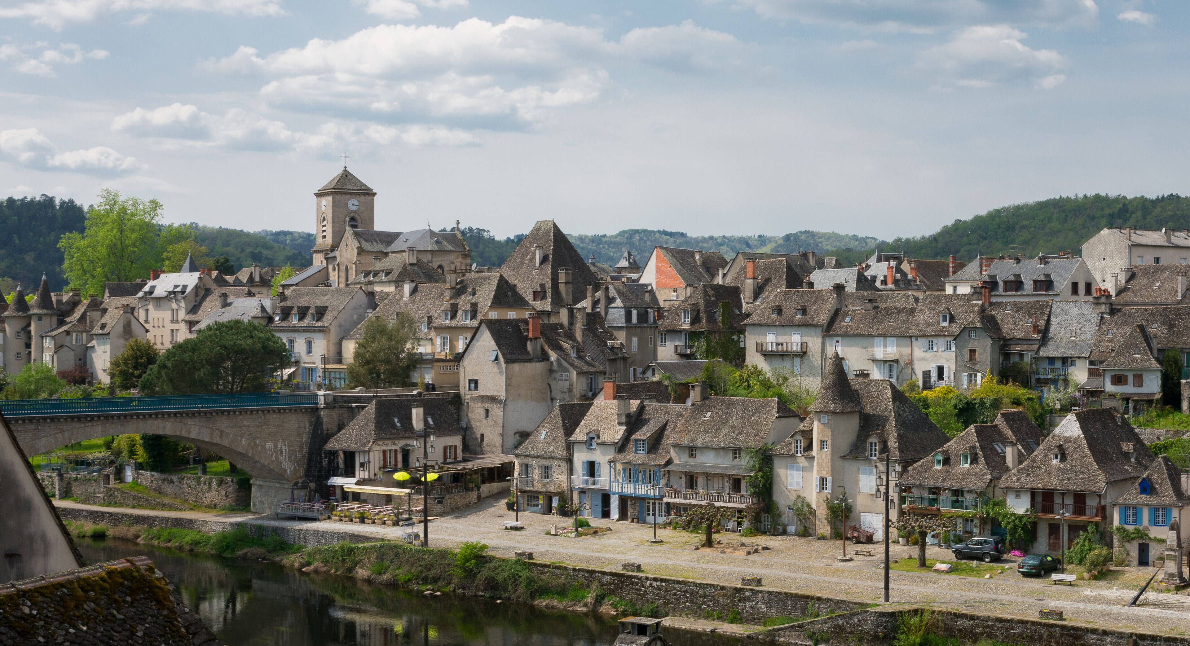 A historic town with stone buildings, a river, and a bridge.