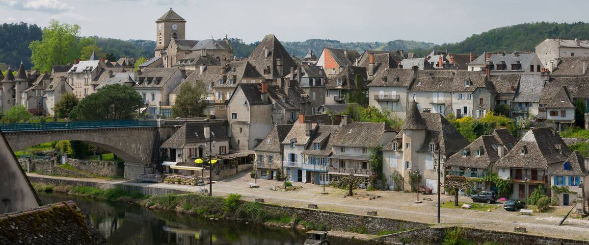 A historic town with stone buildings, a river, and a bridge.