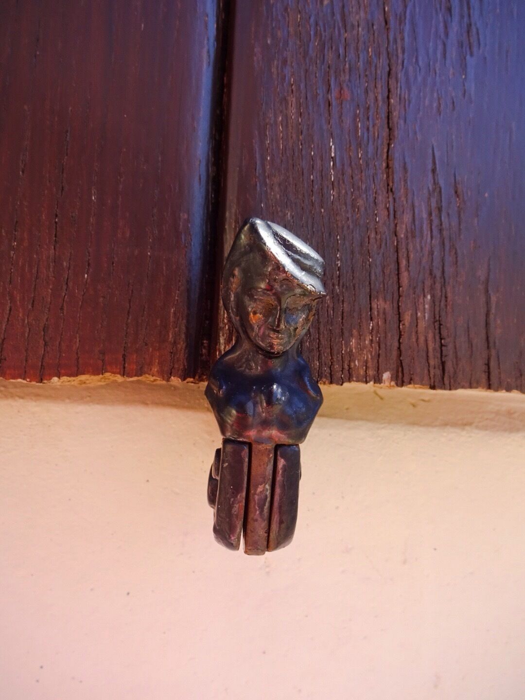 A small, dark-colored figurine with a shiny top, placed on a light-colored surface against a wooden background.