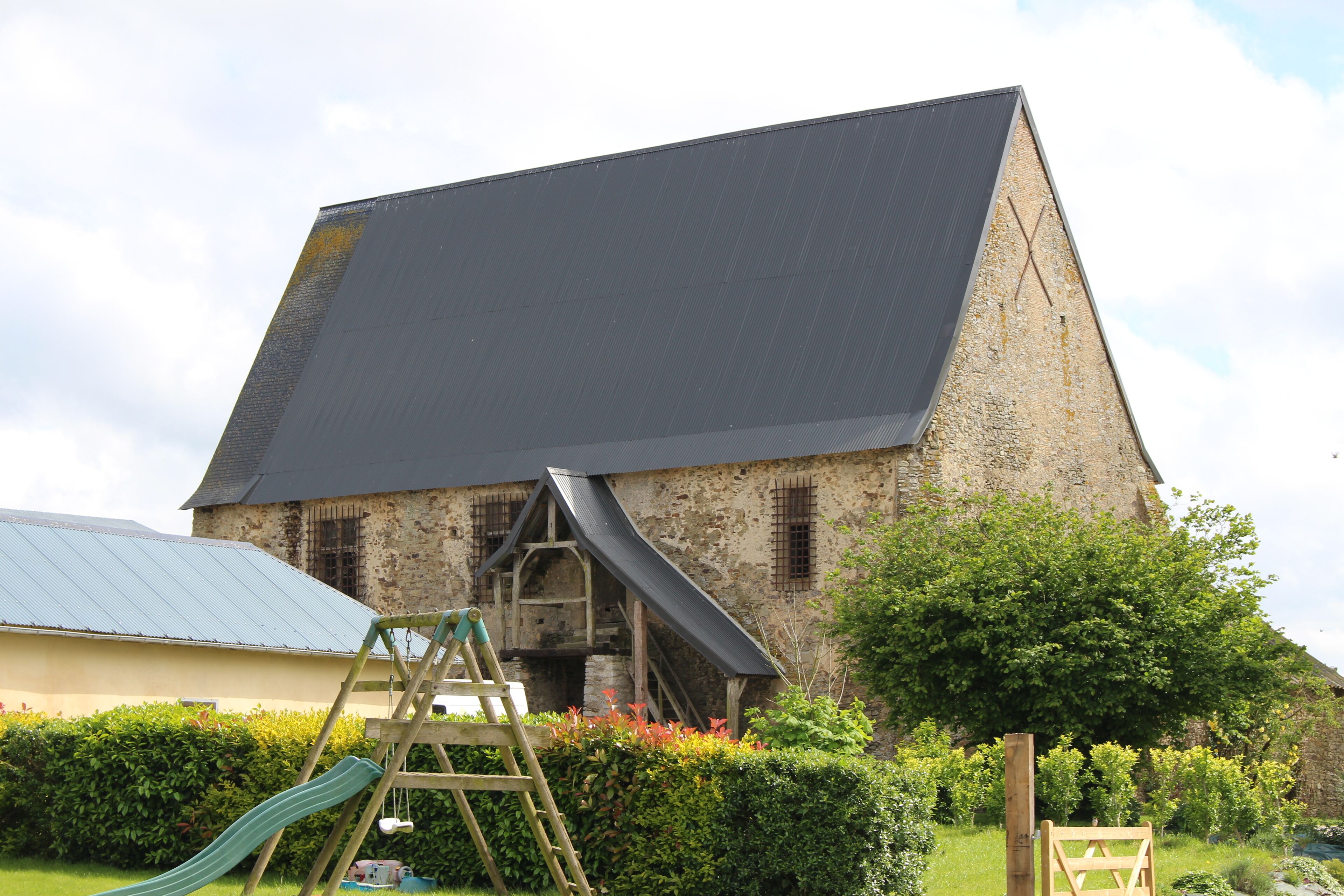 A large stone building with a steep roof and a wooden ladder leading up to a small platform.
