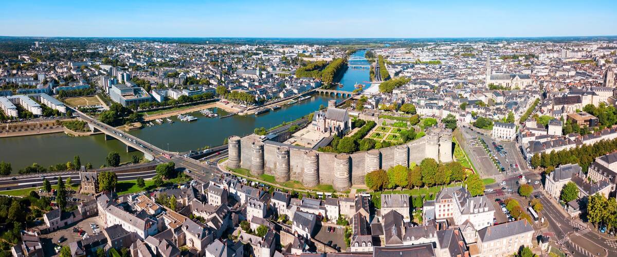 An aerial view of a city with a prominent castle, a river, and a bridge.