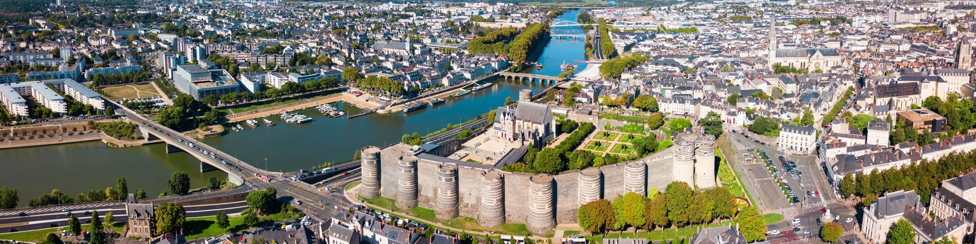 An aerial view of a city with a prominent castle, a river, and a bridge.