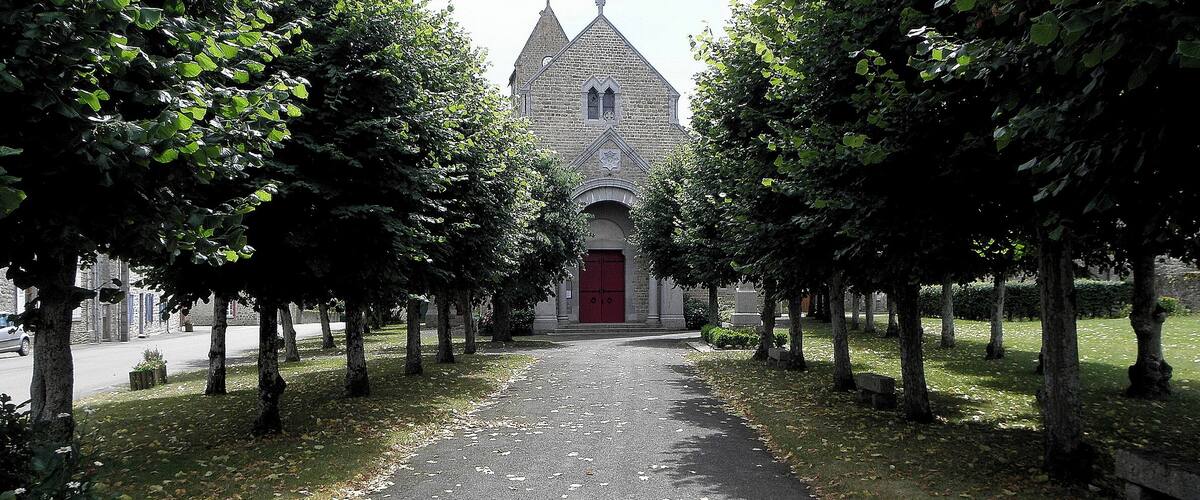 A pathway lined with trees leading to a church with a red door.